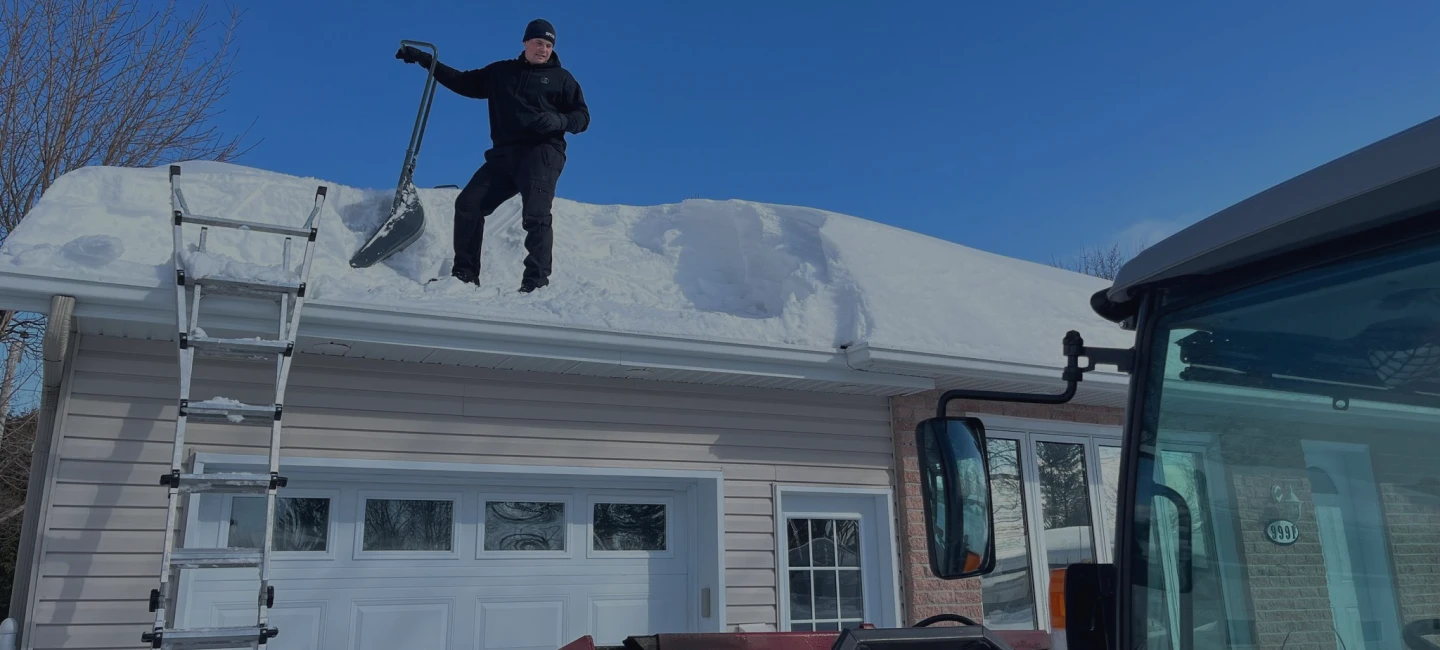 Un employé d’À Point déneigement qui déneige une toiture.